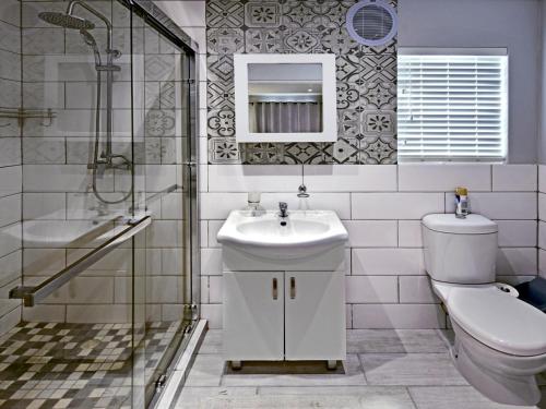 een badkamer met een wastafel, een toilet en een douche bij La Rochelle Cottage in Franschhoek