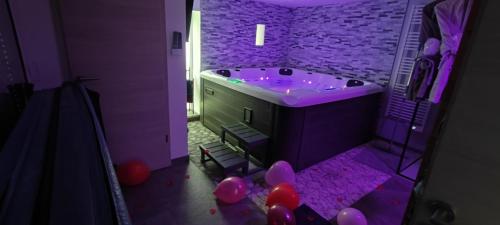 uma casa de banho roxa com balões e uma banheira com iluminação roxa em Gîte Ange ou Démon, love room, jacuzzi, sauna, spa em Benfeld