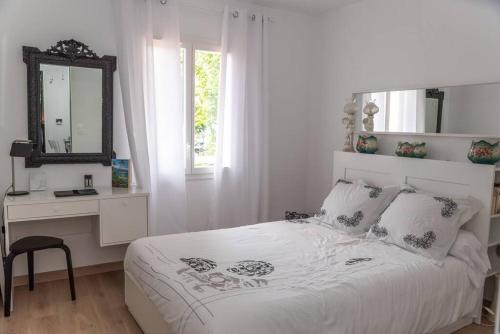 ein weißes Schlafzimmer mit einem Bett und einem Spiegel in der Unterkunft Maison de vacances chaleureuse à 600mdu Bassin in Andernos-les-Bains