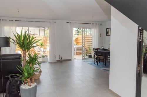 ein Wohnzimmer mit Topfpflanzen und ein Esszimmer in der Unterkunft Maison de vacances chaleureuse à 600mdu Bassin in Andernos-les-Bains