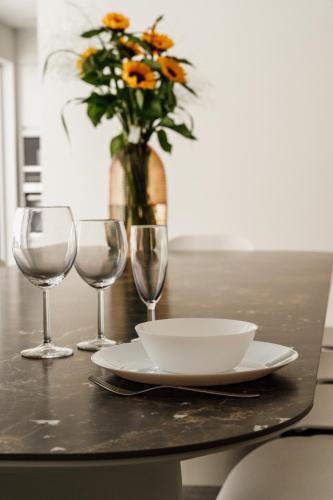 a table with a plate and two glasses and a vase with flowers at Befour Vakantiewoning in Aalst
