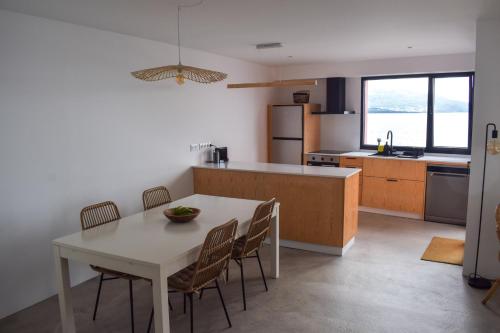 una cocina con una mesa y sillas blancas y una encimera. en Terreiro Ocean House - Sea View en São Roque