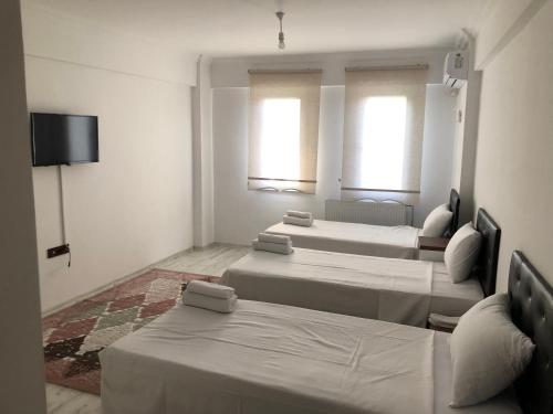 um quarto com três camas e uma televisão e duas janelas em edr ulus 22otel em Edirne