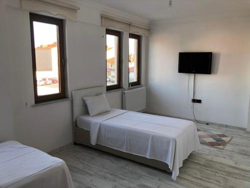 a white bedroom with two beds and a tv at edr ulus 22otel in Edirne