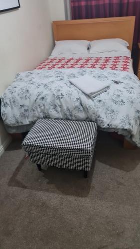 a bed with a blanket and a suitcase on it at Curly Curves in North Woolwich
