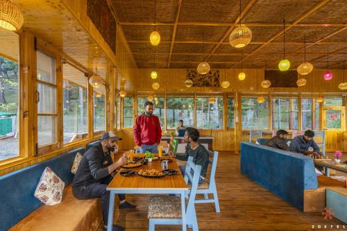 um grupo de pessoas sentadas numa mesa num restaurante em Zostel Pahalgam em Pahalgam