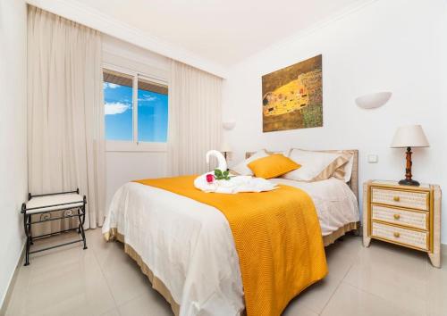 ein weißes Schlafzimmer mit einem Bett mit einer gelben Decke in der Unterkunft EUREKA Sea Views & Comfort in Cala Millor