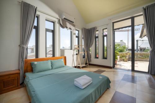 um quarto com uma cama azul e janelas grandes em S Villa Đà Nẵng Gần Biển em Da Nang