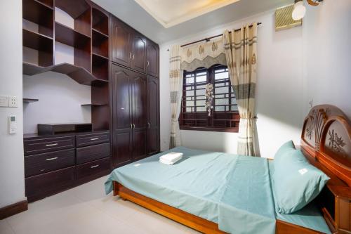 a bedroom with a bed and wooden cabinets and a window at S Villa Đà Nẵng Gần Biển in Da Nang