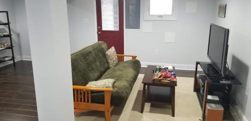 a living room with a green couch and a tv at English Basement Suite in Petworth, Washington, DC -- FREE off-street parking, walk to Metro and restaurants in Washington, D.C.