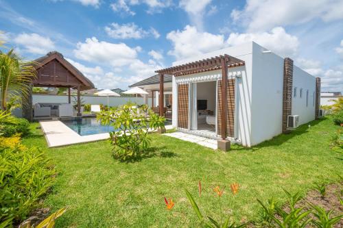 a backyard with a pool and a house at VILLA LILOU, Splendide villa au centre de Grand Baie in Grand Baie