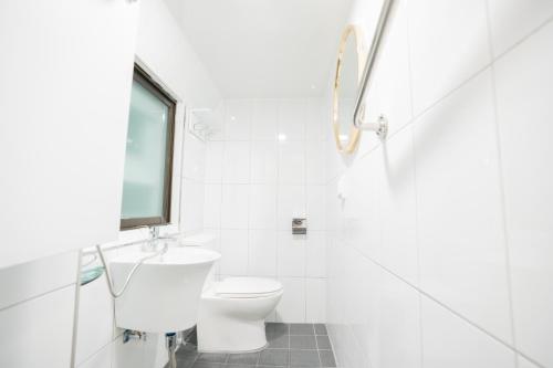 a white bathroom with a toilet and a window at Huayuanhouse HQ in hongdae in Seoul