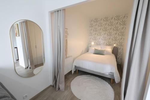 1 dormitorio con cama blanca y espejo en Lavilladouce, en Moret-sur-Loing