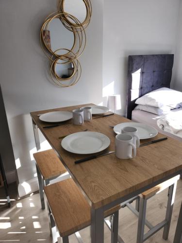 a wooden table with plates and mugs on it at Southernwood - Wantage Road Apt 2 in Didcot