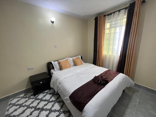 a bedroom with a large bed and a window at Kef Apartments in Nanyuki