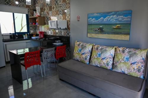 a living room with a couch and a kitchen with a table at Chalés Casuarinas in Japaratinga