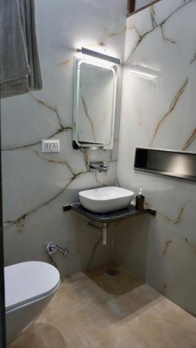 a bathroom with a sink and a toilet and a mirror at Mandakini Homestay in Varanasi
