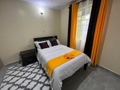 a bedroom with a bed and a window with orange curtains at Kef Apartments in Nanyuki