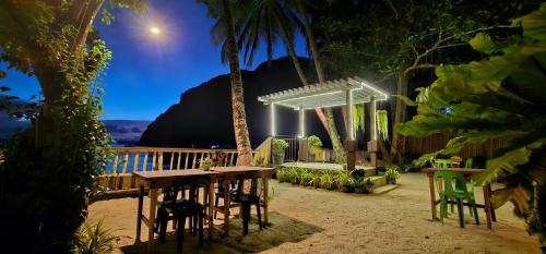 una mesa y sillas en la playa por la noche en Mina Grande Beach Cottages en El Nido