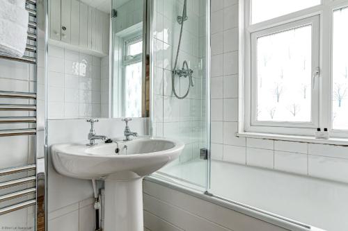 uma casa de banho branca com um lavatório e uma janela em Lavender House em Oxford