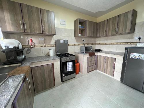 a kitchen with wooden cabinets and a stove top oven at Kef Apartments in Nanyuki