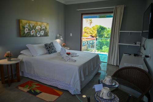 a bedroom with a bed and a large window at Chalés Casuarinas in Japaratinga