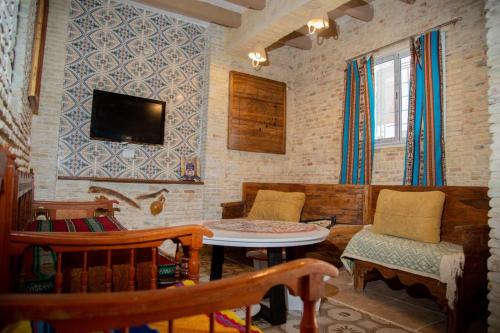 a living room with a tv and a table and chairs at Appartement Berbère in Tozeur