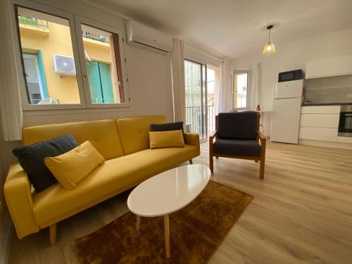 un salon avec un canapé jaune et une table dans l'établissement Appartement en bord de mer 1, à Banyuls-sur-Mer