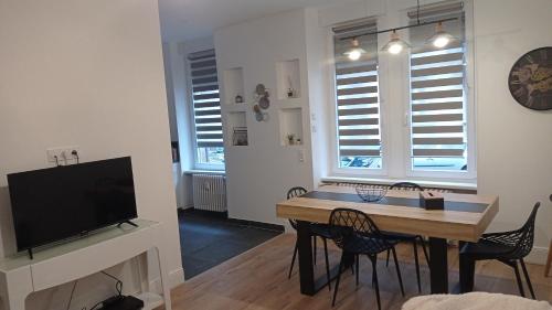 a living room with a table and chairs and a television at Appart 3p RDC Orangerie- Parlement européen in Strasbourg