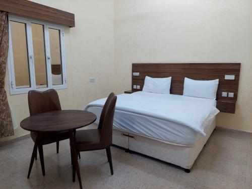 a bedroom with a bed and a table and chairs at Hotel Ain Safnan Room&Flats فندق عين صفنان غرف&شقق in Sanāw