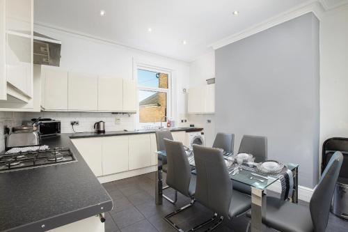 a kitchen with white cabinets and a table and chairs at Lytham Place in Blackpool