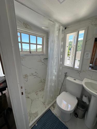 a white bathroom with a toilet and a sink at Cabana do Mar in Angra dos Reis