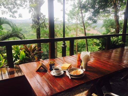 een houten tafel met een kom eten op een balkon bij Phu Pha Nam Resort in Dan Sai