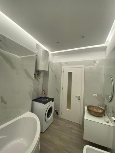 a white bathroom with a toilet and a sink at Riar Apartaments in Korçë