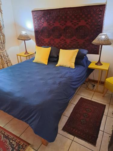 a bed with blue sheets and yellow pillows in a room at Ellipsis Cottage in Knysna
