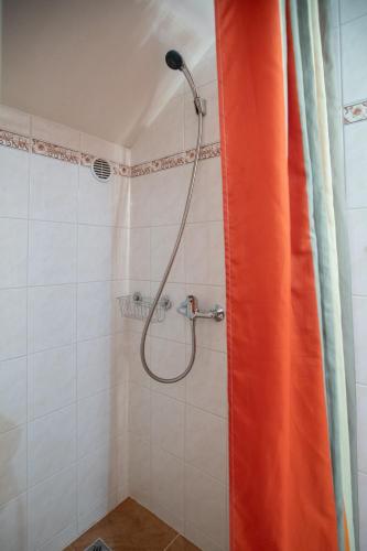 a shower with an orange curtain in a bathroom at Penzion Pod kapličkou in Tišnov
