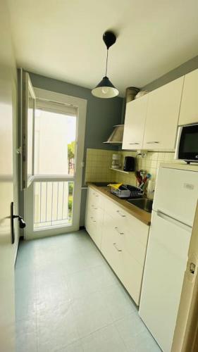 une cuisine avec un réfrigérateur blanc et une fenêtre dans l'établissement Beau T2 dans résidence calme 5 Toits et Mois, à La Grande Motte