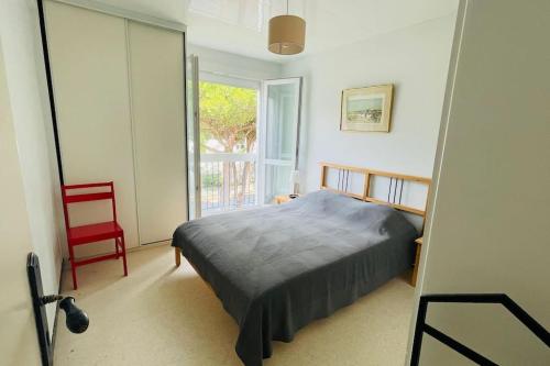 una camera da letto con un letto e una sedia rossa di Beau T2 dans résidence calme 5 Toits et Mois a La Grande-Motte