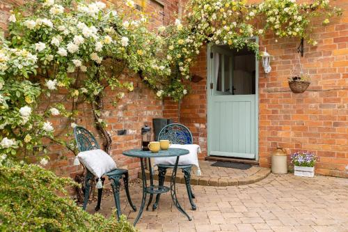 a patio with a table and chairs in front of a brick building at The Kiln in Little Marcle