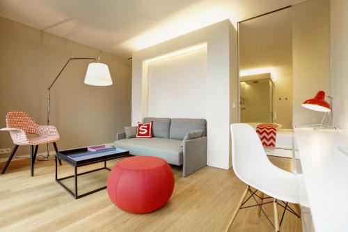 a living room with a couch and a red stool at Smartcity Designhotel in Hannover
