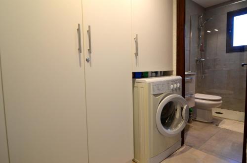 une salle de bains avec lave-linge et toilettes dans l'établissement ATENES 12, à L'Estartit