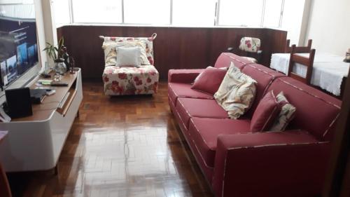 a living room with a red couch and a television at Copacabana aconchegante in Rio de Janeiro