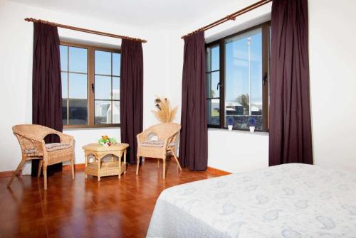 1 dormitorio con 1 cama, sillas y ventanas en Villa Capricho, en Playa Blanca