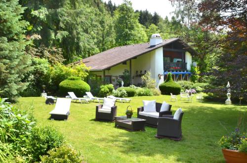 einen Garten mit Sofas und Stühlen vor einem Haus in der Unterkunft Wellness und Romantik Hotel Helmboldt in Bad Sachsa