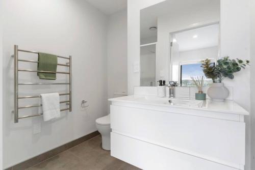 a white bathroom with a sink and a mirror at Contemporary Urban Retreat in Auckland