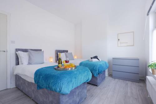 two beds with blue covers in a bedroom at Newly Refurbished House - Close to Town Centre -Free Parking, Super-Fast Wifi, Smart TV with Netflix by Yoko Property in Northampton