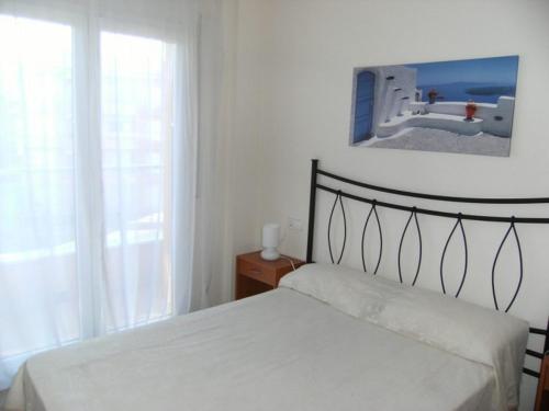 1 dormitorio con 1 cama con una foto en la pared en Apartamentos Athenea en Ampurias