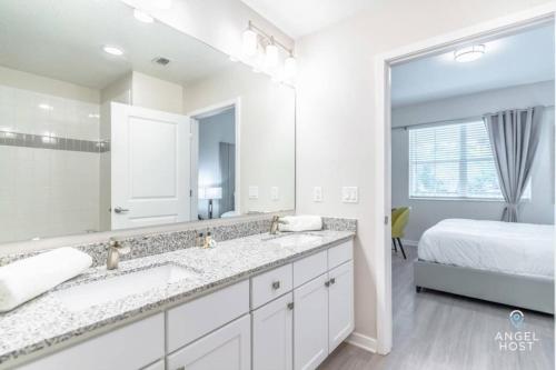 een witte badkamer met een grote spiegel en een bed bij Apartment at Vista Cay Resort in Orlando