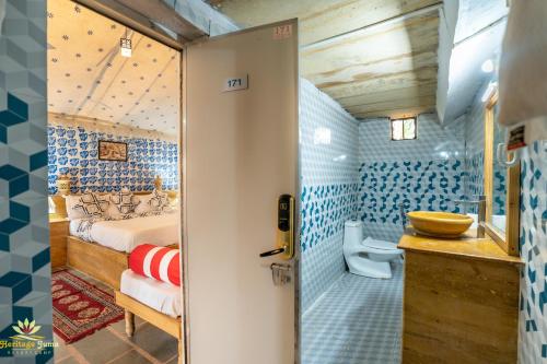 um quarto com uma cama e uma casa de banho com azulejos azuis em Heritage Juma Resort with swimming pool em Jaisalmer