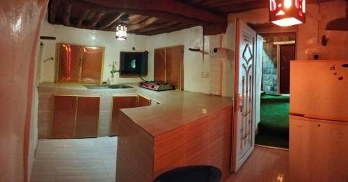 a large kitchen with a counter and a refrigerator at نزل الريف التراثيه in Al ‘Aqar